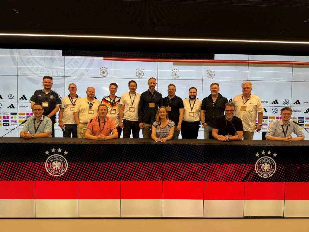Gruppenbild am Podium des Presseraums des Deutschen Fußball-Bundes, hinter den Gästen eine Logowand mit DFB-Adler und Sponsorenlogos.